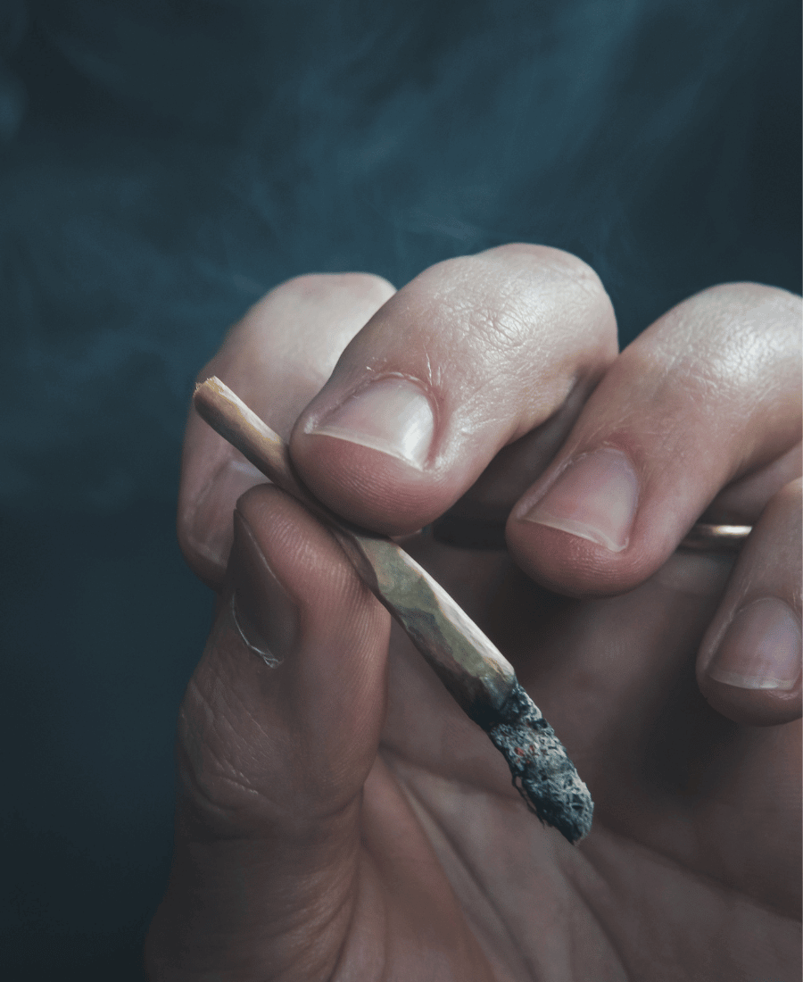 Kéz tart egy izzó kannabisz Joint-ot